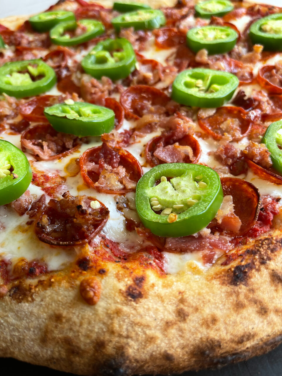 Close up of Side Slice Pies spicy pig pizza with pepperoni, bacon and jalapeno